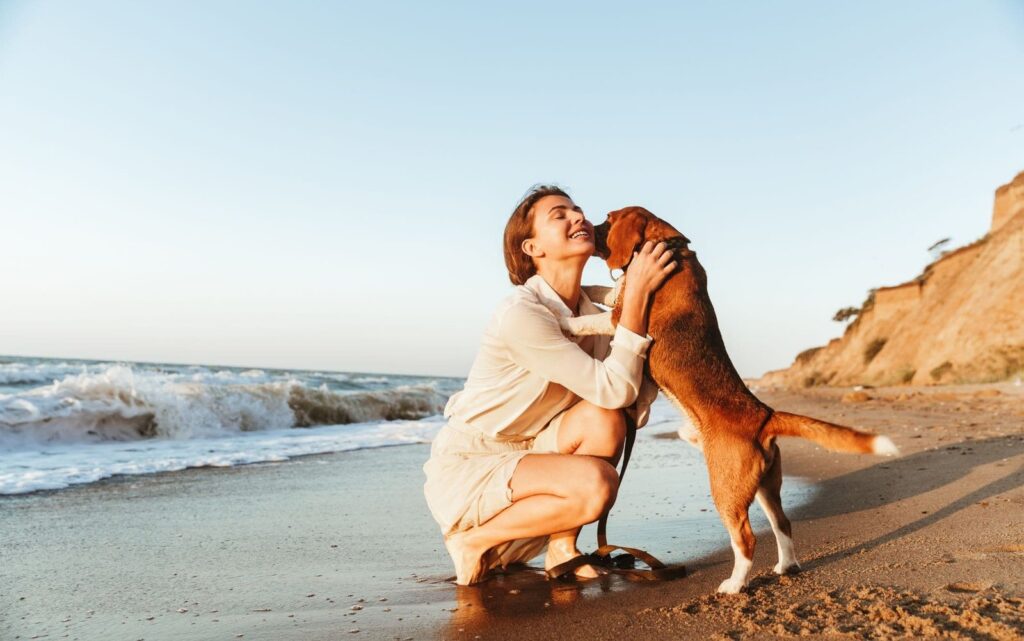 frau_mit_ihrem_hund_am_strand_am_spielen